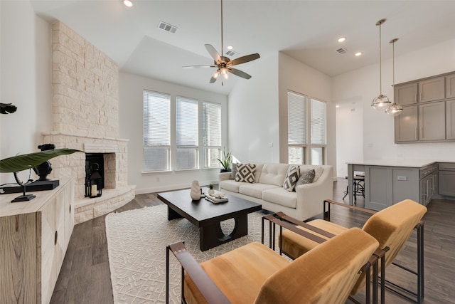 living room featuring ceiling fan, dark hardwood / wood-style flooring, lofted ceiling, and a fireplace