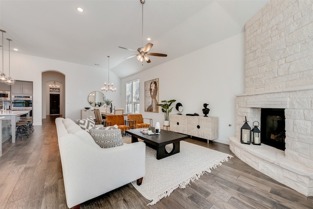 living room featuring a fireplace, ceiling fan with notable chandelier, dark hardwood / wood-style floors, and lofted ceiling