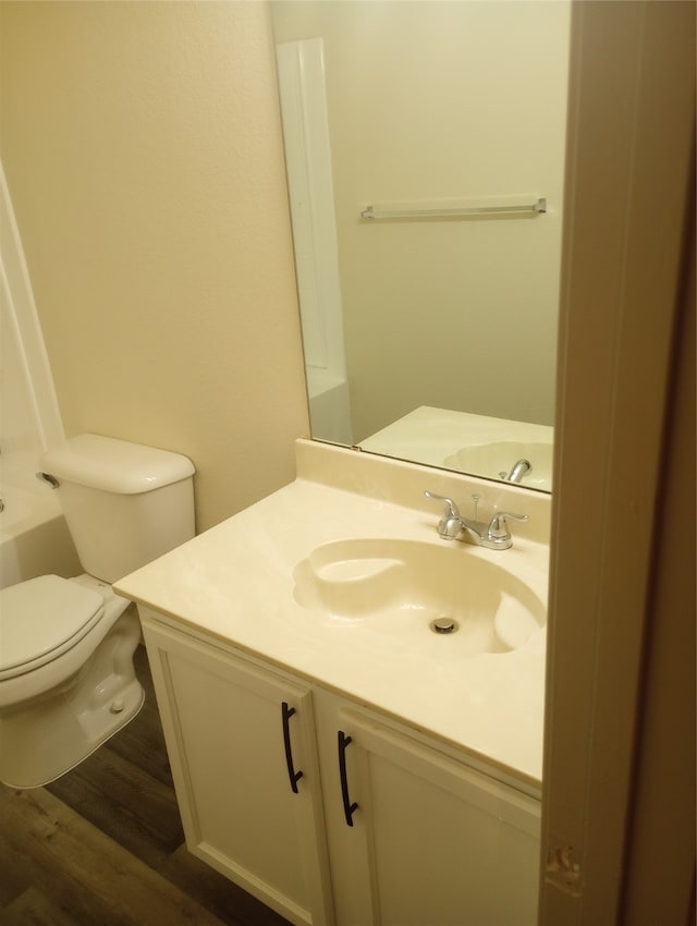 bathroom featuring hardwood / wood-style floors, vanity, toilet, and a tub