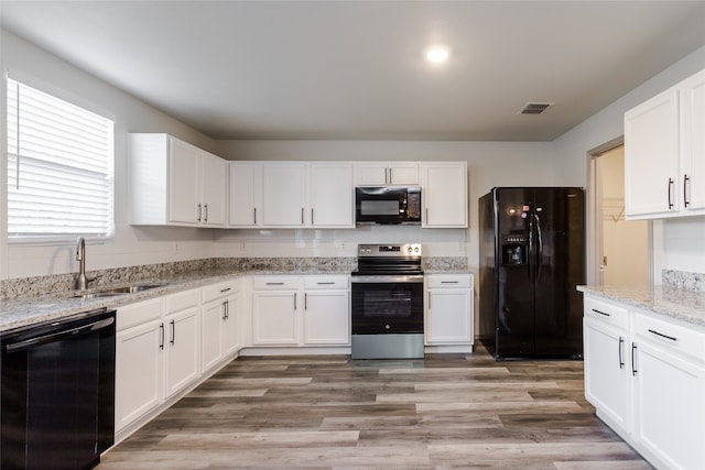 kitchen featuring white cabinetry, sink, black appliances, and light wood-type flooring