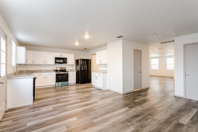 kitchen with black appliances, white cabinets, sink, and light hardwood / wood-style flooring