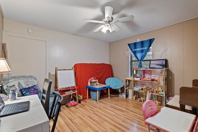 office area with hardwood / wood-style flooring, ceiling fan, and wood walls