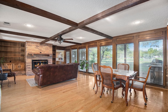 dining space featuring light hardwood / wood-style flooring, beamed ceiling, and a textured ceiling