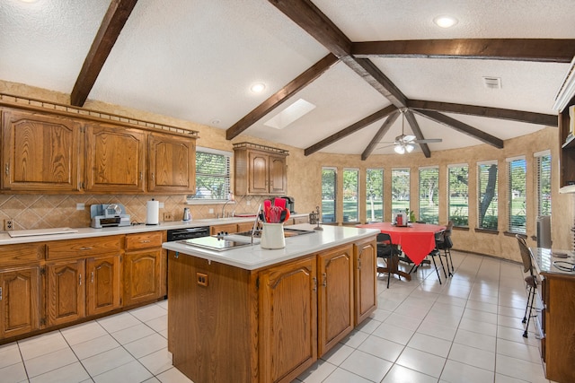 kitchen with ceiling fan, vaulted ceiling with beams, backsplash, a textured ceiling, and a kitchen island