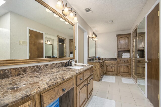 bathroom with tile patterned flooring, vanity, and a textured ceiling