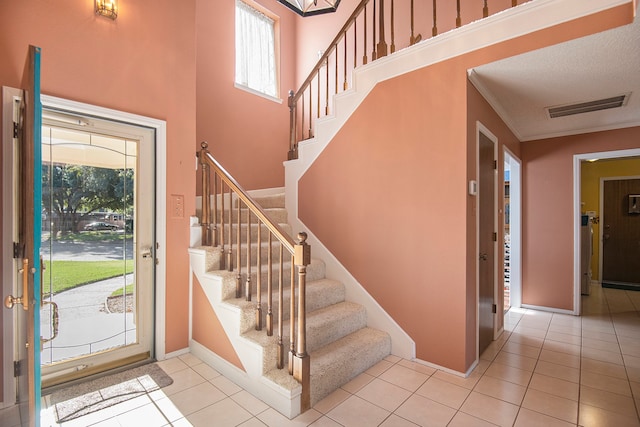 foyer entrance featuring light tile patterned floors, a textured ceiling, and a high ceiling