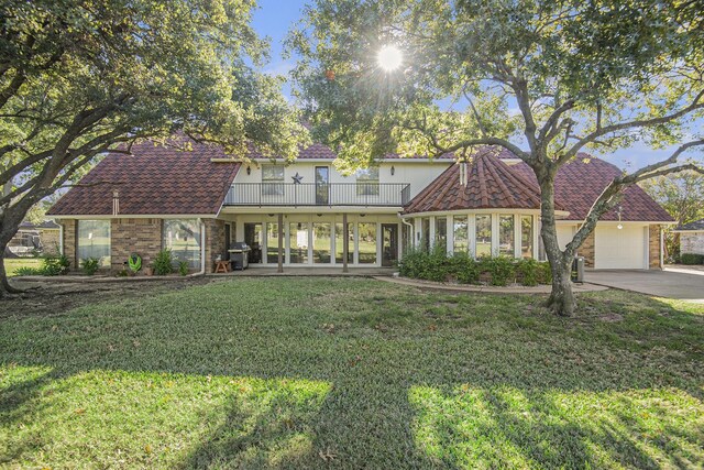 view of front of property featuring french doors, a balcony, a front yard, and a garage