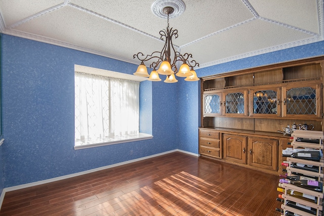 unfurnished dining area with a textured ceiling, crown molding, indoor bar, an inviting chandelier, and dark hardwood / wood-style floors