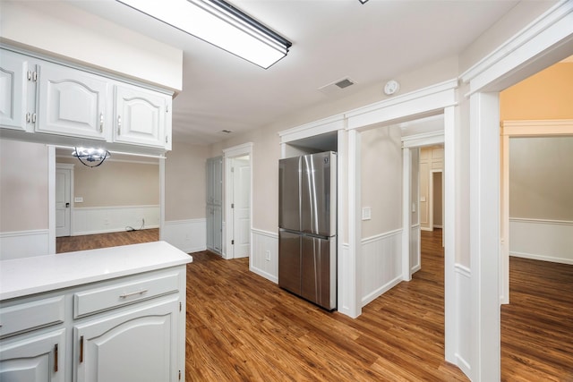 kitchen with stainless steel refrigerator, hardwood / wood-style flooring, and white cabinets