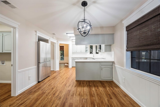 kitchen featuring white cabinets, wood-type flooring, stainless steel fridge, and kitchen peninsula