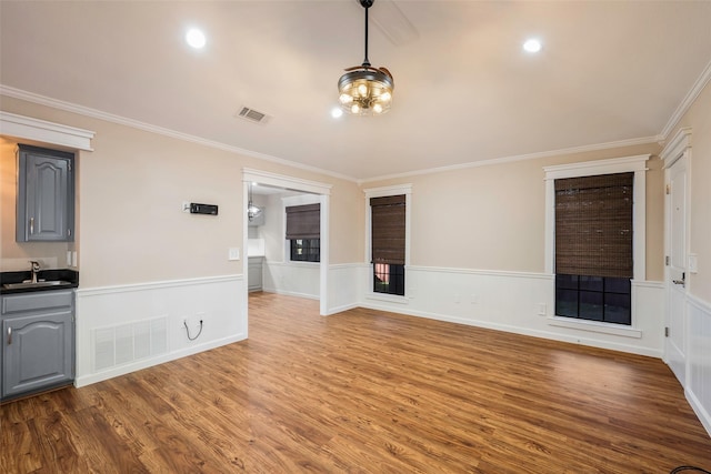 unfurnished living room featuring crown molding, sink, and hardwood / wood-style floors