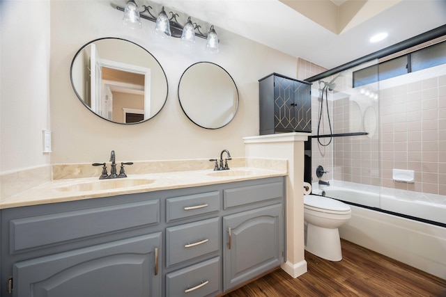 full bathroom with hardwood / wood-style flooring, vanity, combined bath / shower with glass door, and toilet