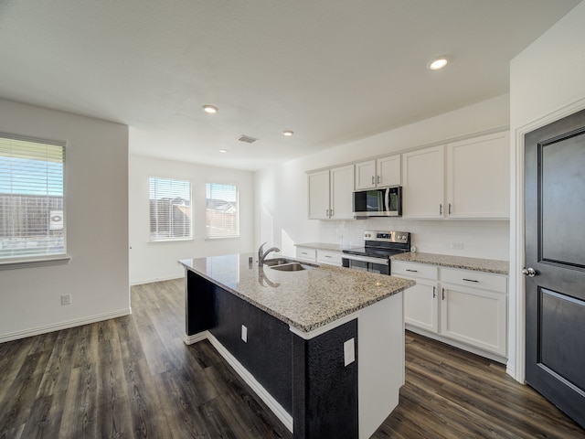 kitchen featuring stainless steel appliances, white cabinetry, plenty of natural light, and a center island with sink