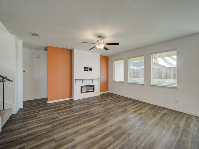 unfurnished living room featuring ceiling fan, a large fireplace, and dark hardwood / wood-style floors