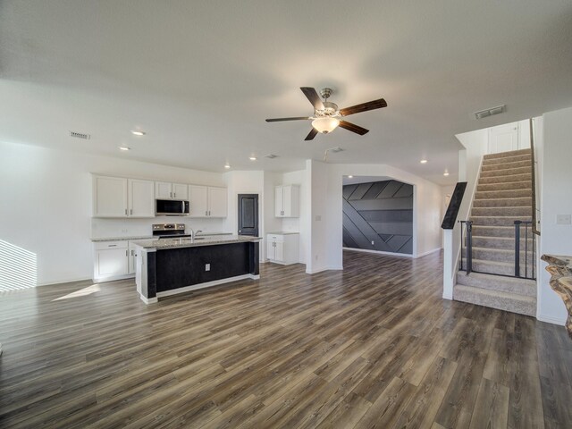 kitchen featuring white cabinets, ceiling fan, an island with sink, dark hardwood / wood-style flooring, and stainless steel appliances