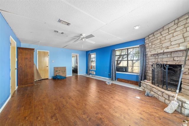 unfurnished living room featuring a fireplace, ceiling fan, wood-type flooring, and a textured ceiling