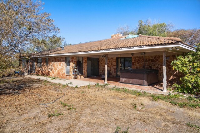 rear view of property featuring a hot tub