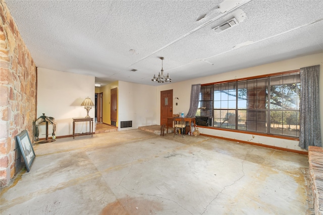 interior space featuring concrete flooring, a textured ceiling, and an inviting chandelier