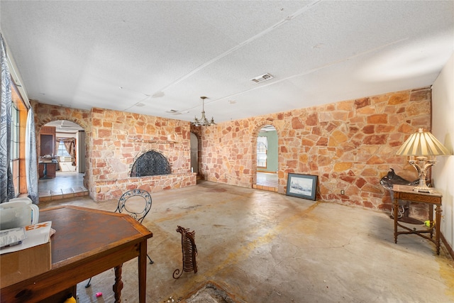 living room with a fireplace, concrete flooring, a textured ceiling, and an inviting chandelier