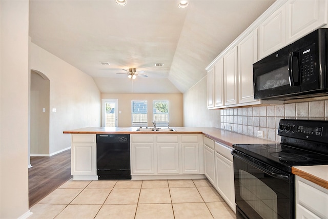 kitchen with kitchen peninsula, white cabinetry, black appliances, and lofted ceiling