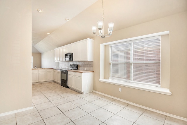 kitchen featuring black appliances, light tile patterned floors, decorative light fixtures, white cabinetry, and lofted ceiling