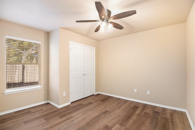 unfurnished bedroom with ceiling fan, a closet, and wood-type flooring