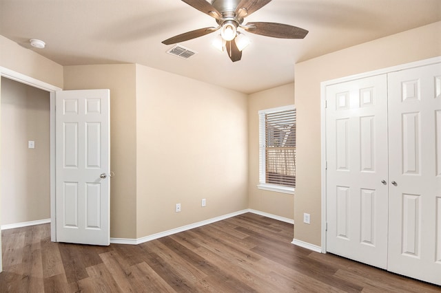 unfurnished bedroom with ceiling fan, a closet, and wood-type flooring