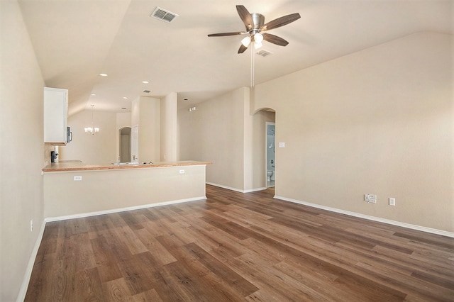 unfurnished living room featuring vaulted ceiling, ceiling fan with notable chandelier, and dark hardwood / wood-style floors