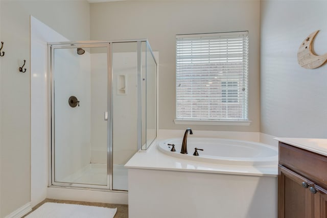 bathroom with independent shower and bath, vanity, and a healthy amount of sunlight