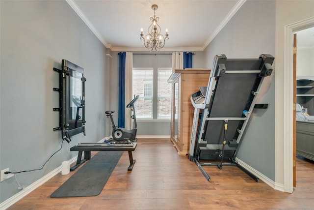 exercise room featuring ornamental molding, hardwood / wood-style flooring, and a notable chandelier