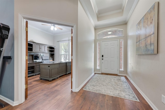 foyer entrance with ceiling fan, dark wood-type flooring, and ornamental molding