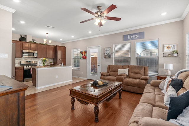 living room with ceiling fan, plenty of natural light, wood-type flooring, and ornamental molding