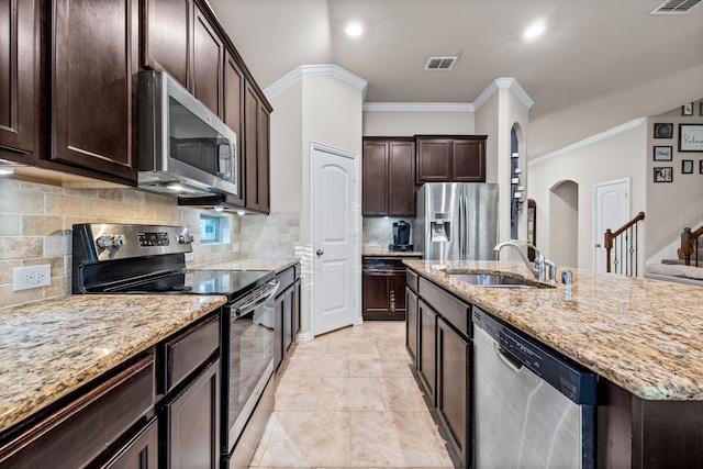 kitchen featuring a center island with sink, crown molding, sink, decorative backsplash, and appliances with stainless steel finishes