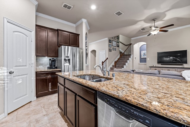 kitchen featuring sink, light stone countertops, ornamental molding, dark brown cabinets, and stainless steel appliances