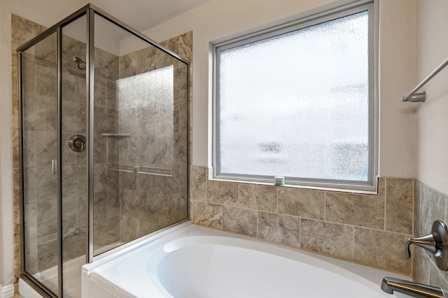 bathroom featuring independent shower and bath and a healthy amount of sunlight