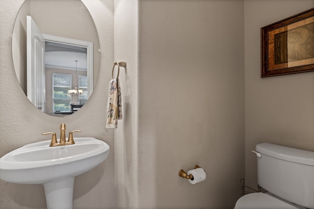 bathroom featuring toilet, sink, and a chandelier