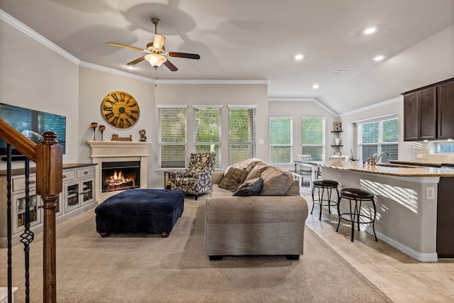 living room with ceiling fan, sink, vaulted ceiling, light tile patterned flooring, and ornamental molding