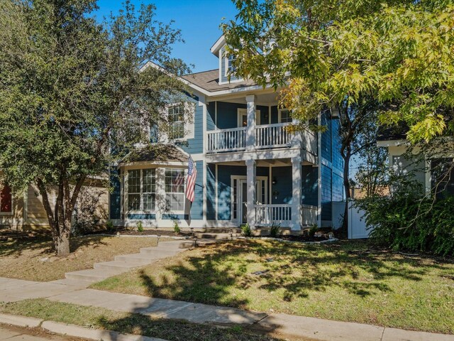 view of front of home with covered porch, a balcony, and a front lawn