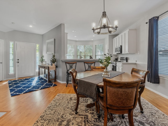 dining room with sink, a chandelier, and light hardwood / wood-style floors