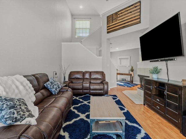 living room with light wood-type flooring and high vaulted ceiling