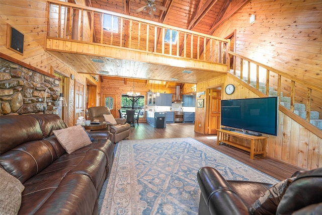 living room with wooden ceiling, beamed ceiling, wooden walls, ceiling fan with notable chandelier, and hardwood / wood-style flooring