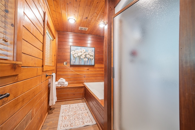 bathroom with wooden walls, wooden ceiling, a bath, and hardwood / wood-style flooring