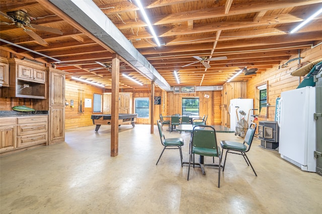 basement featuring white fridge, a wood stove, wood walls, and billiards