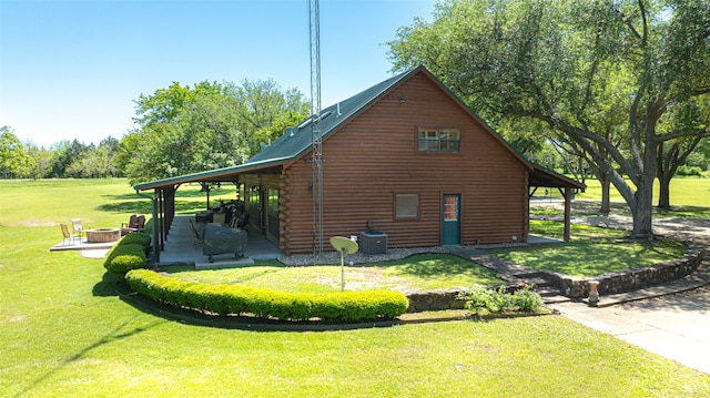 view of side of home featuring central air condition unit, a yard, and a fire pit