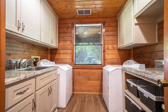 clothes washing area with washing machine and dryer, wooden walls, wooden ceiling, and dark hardwood / wood-style floors