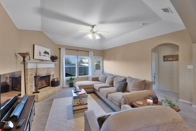 carpeted living room with ceiling fan, vaulted ceiling, and a brick fireplace