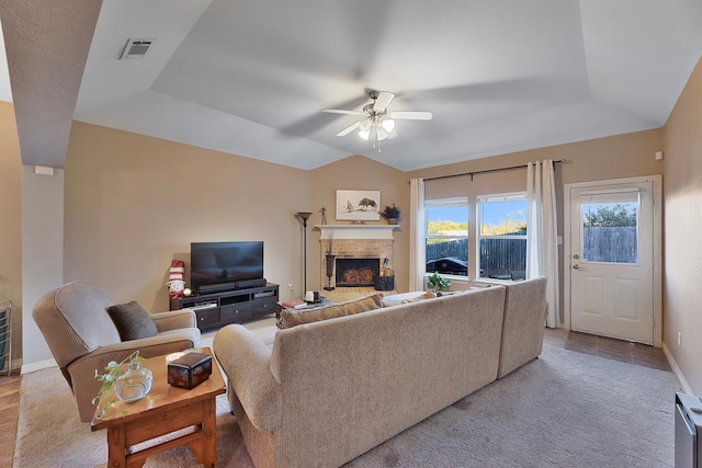 carpeted living room featuring ceiling fan, lofted ceiling, a fireplace, and a raised ceiling