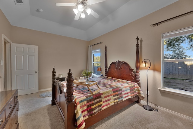 bedroom with ceiling fan, a tray ceiling, and light carpet