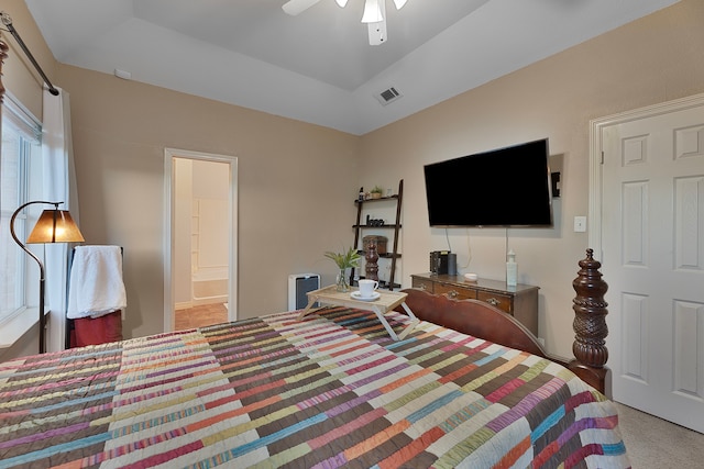 bedroom with ceiling fan, a raised ceiling, light carpet, and connected bathroom