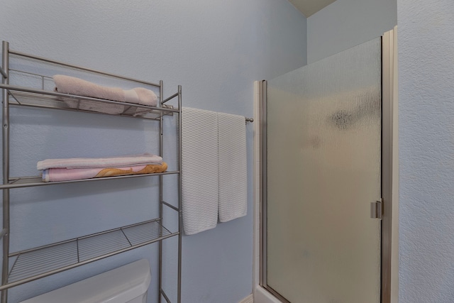 bathroom with toilet and a shower with door